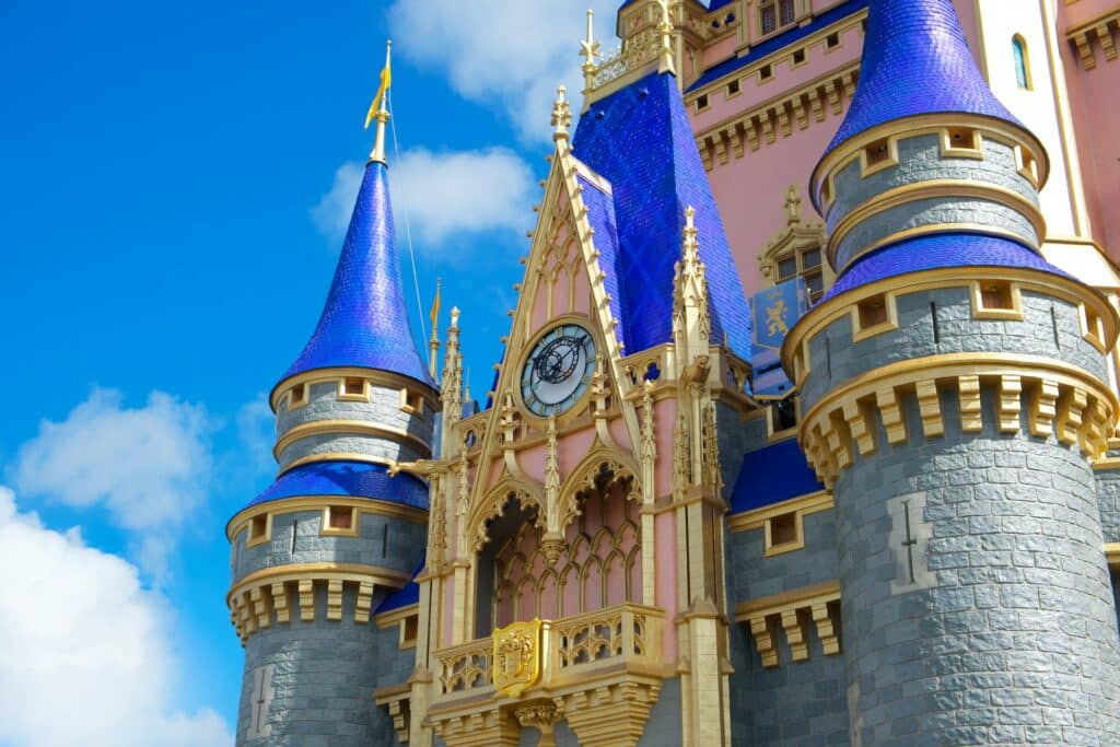 Castelo da Disney em tons de cinza, azul, rosa e detalhes dourados, durante o dia.
