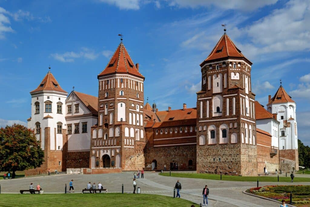 Castelo Mir, um complexo com diversas torres em estilo medieval e com pessoas ao redor na grama, que ilustra o post de chip celular Belarus