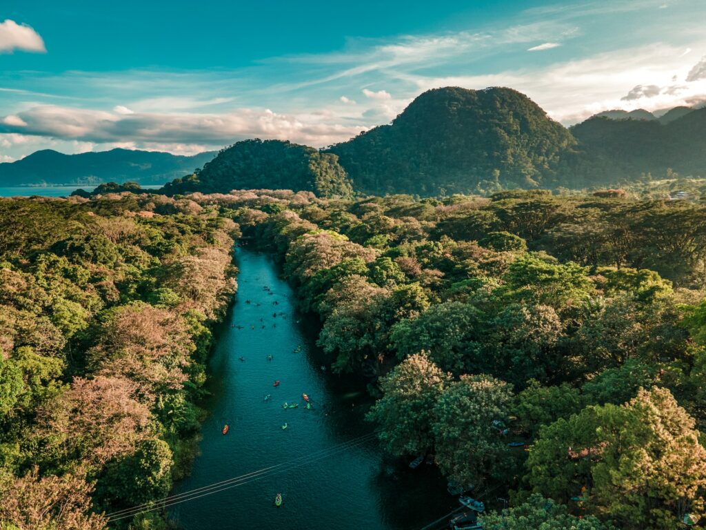 canal no Los Naranjos, Santa Cruz de Yojoa, com caiaques coloridos e uma água muito azul com vegetação densa de ambos os lados, há montanhas de fundo, para ilustrar o post de chip celular Honduras
