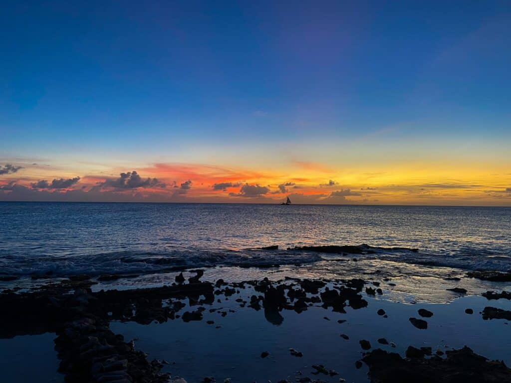 vista do pôr do sol com céu azul e tons de amarelo e laranja em Sint Eustatius and Saba, para ilustrar o post de chip celular Bonaire, com águas e ondinhas leves e áua clara