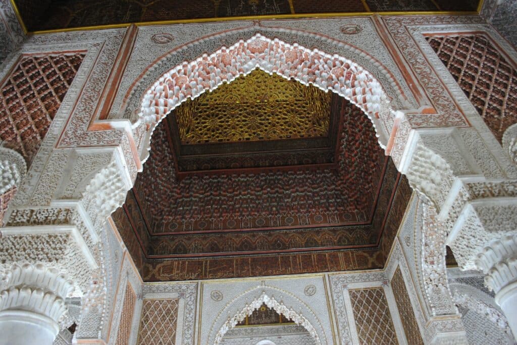 vista do interior dos Túmulos Saadianos, com uma entrada toda trabalhada em branco e detalhes ricamente trabalhados de arabescos em vermelhos e marrons, para ilustrar o post de chip celular Marrakesh