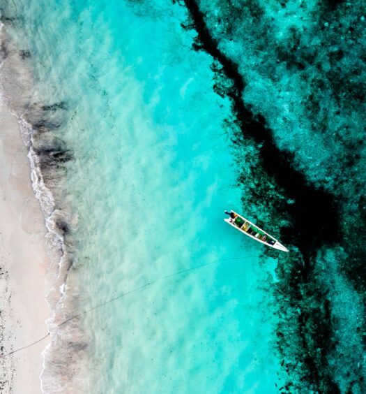 Mar com águas azuis cristalinas em Timor Leste com um barco a deriva.
