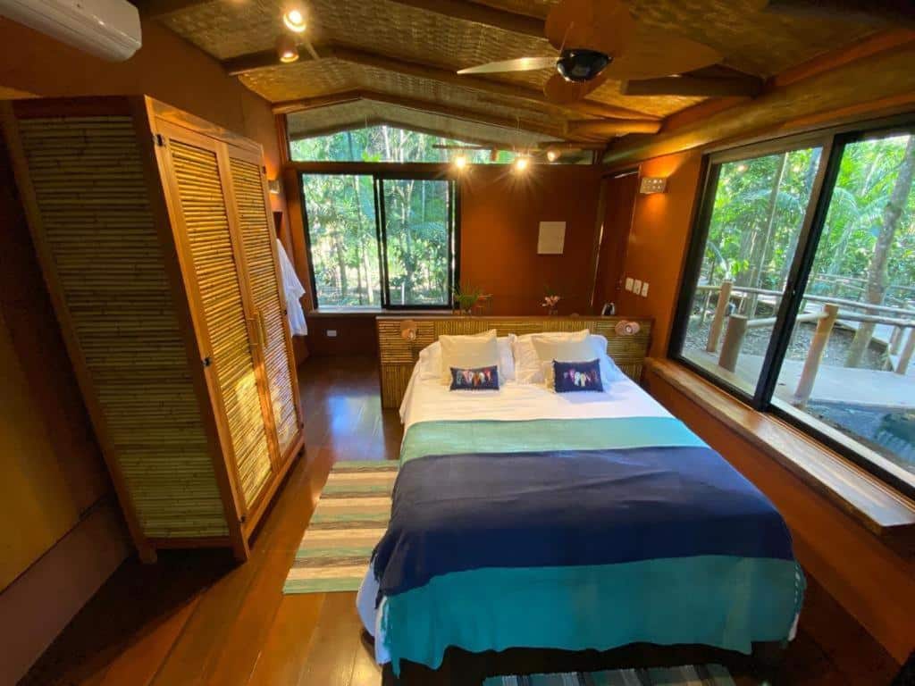 Quarto do Banana Bamboo Ecolodge com uma cama de casal, duas janelas de vidro, alguns móveis de madeira