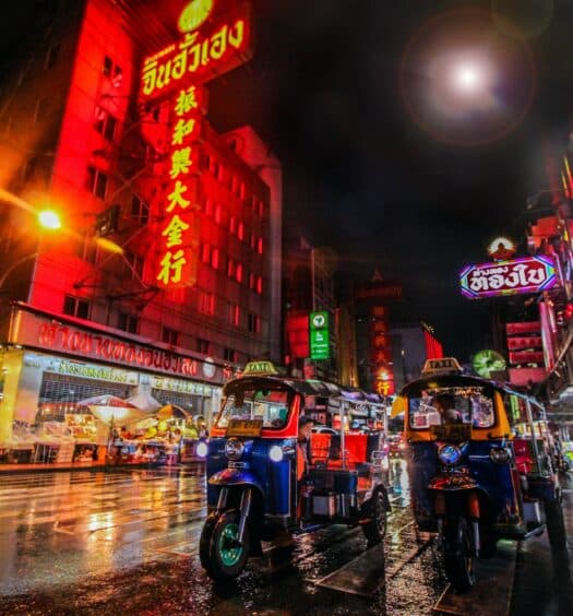 Bangkok Chinatown centro da cidade, carros e transportes passando de noite com comércios iluminados.
