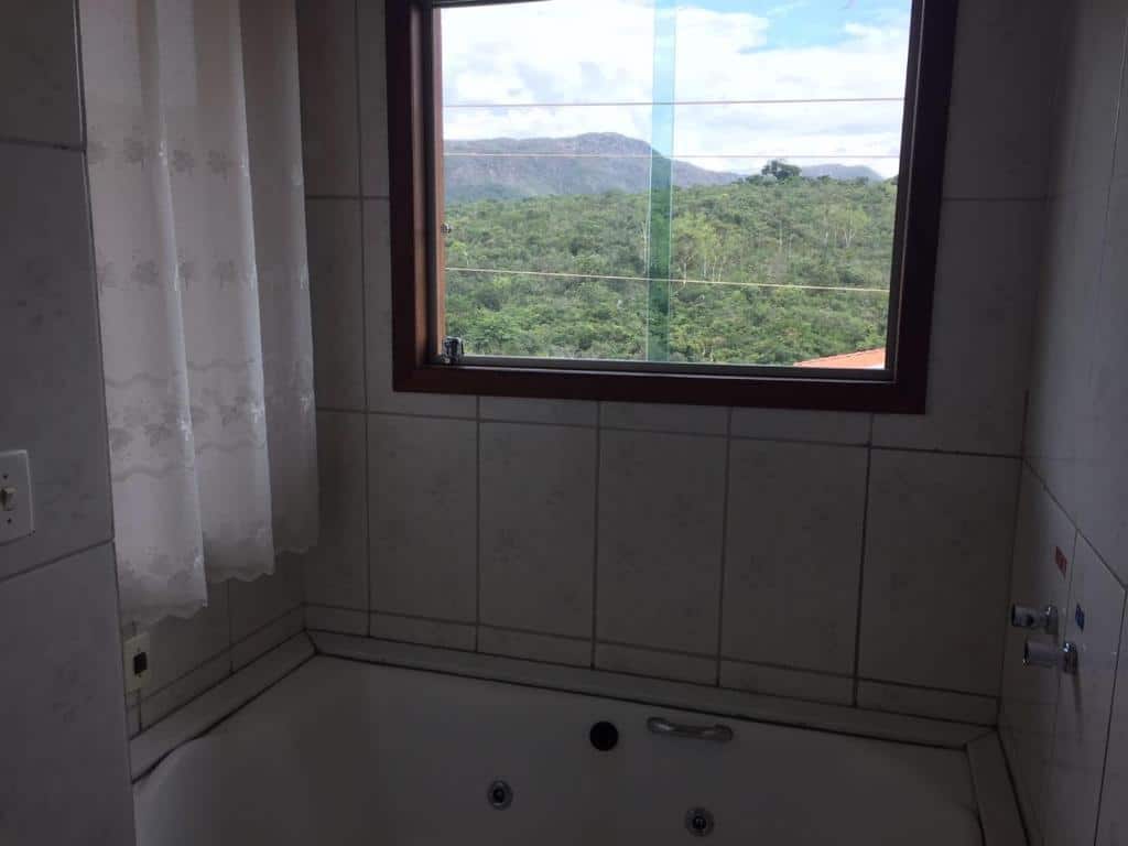banheiro da Chalés Colina de Casa Branca com banheira de hidro e janela de vidro com vista da natureza