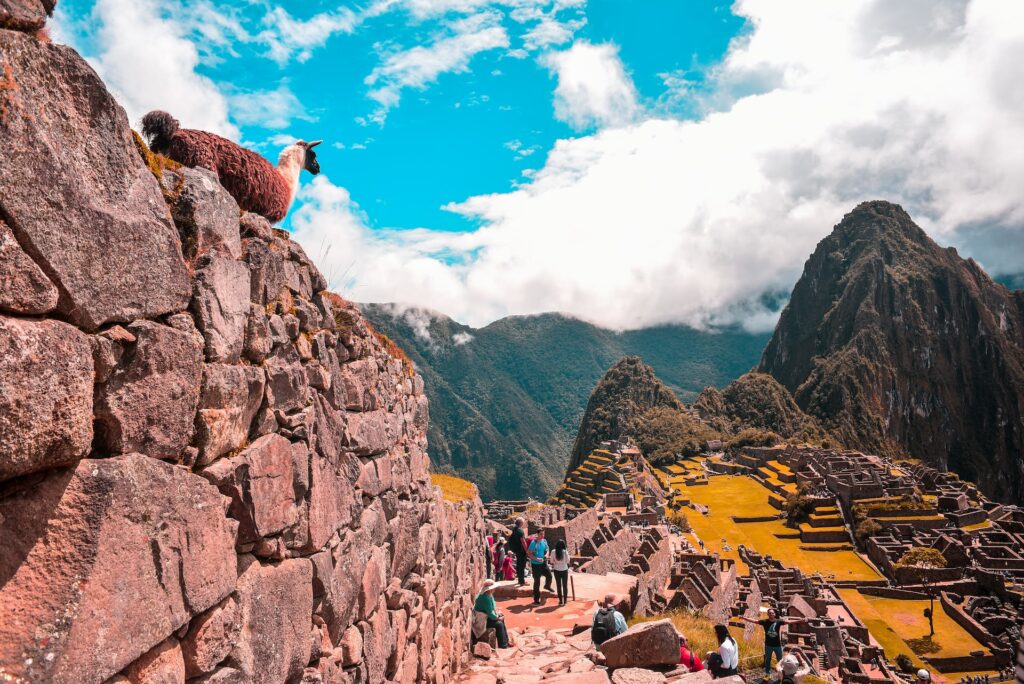 Ruínas de Machu Picchu com muitos turistas andando pelo labirinto de montanhas, escadas e construções antigas