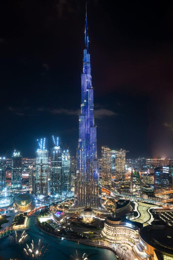 Foto do maior arranha-céu do mundo entre os outros prédios iluminados para ilustrar o post sobre chip de celular para Dubai. - Foto: Timo Volz via Unsplash