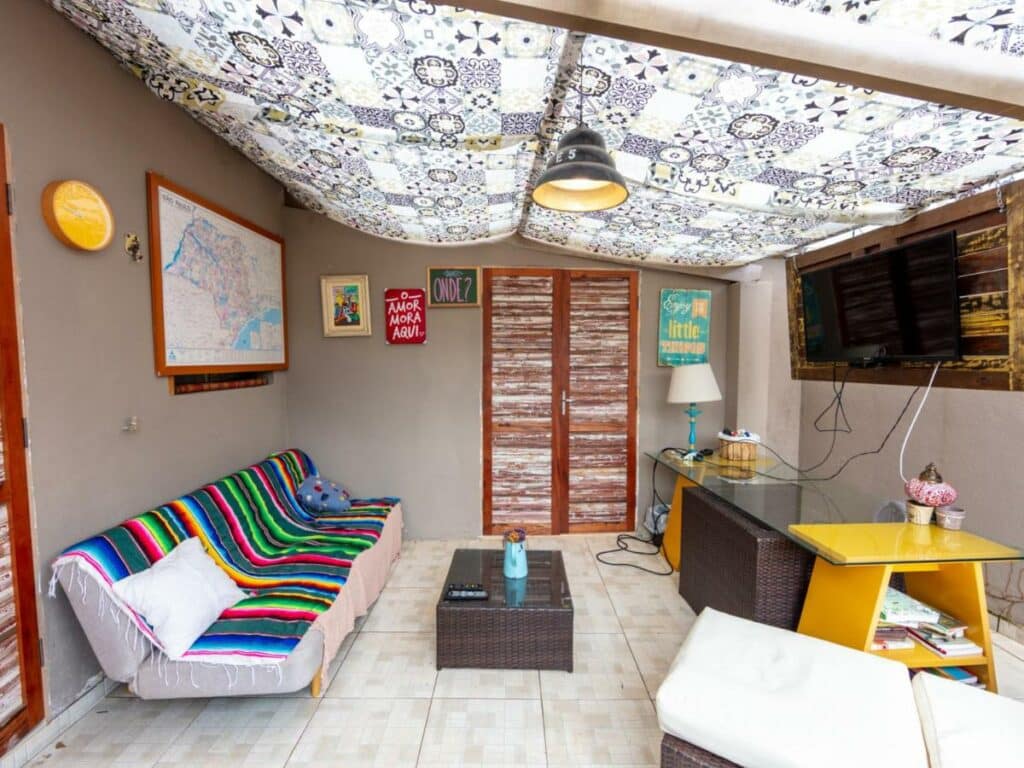 Sala compartilhada do Casa Alma Zen - Hostel Boutique & Bistrô Ubatuba com uma televisão, um sofá, alguns bufês e itens de decoração