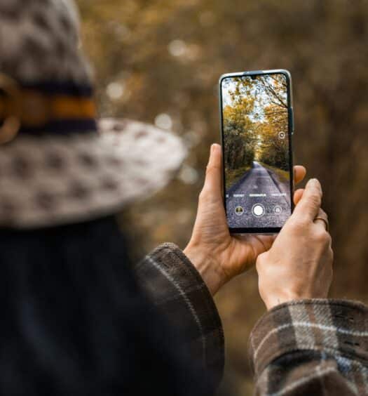 Mulher segurando o celular na mão fotografando alguma paisagem. Representa chip celular Sérvia