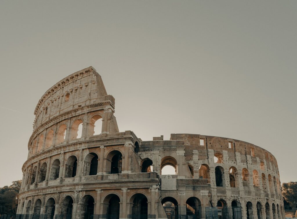 fachada do Coliseu, em Roma, com vários pórticos e um lado mais alto do que o outro em uma espiral redonda