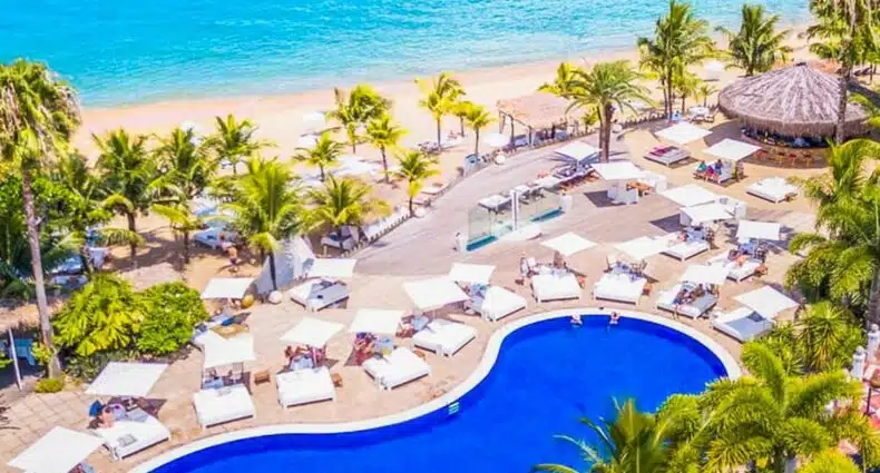 Vista de cima do DPNY Beach Hotel & SPA com uma piscina, algumas palmeiras e logo em seguida já é a praia