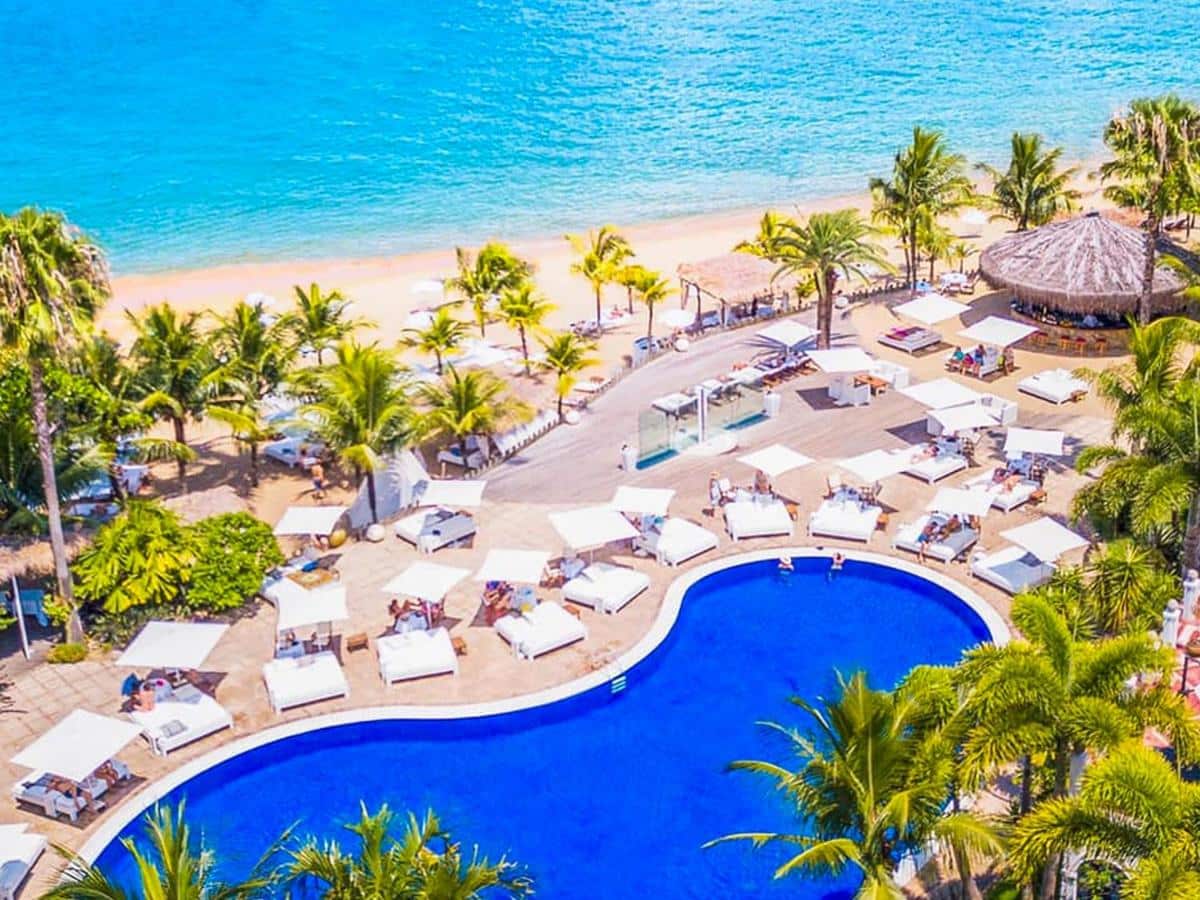 Vista de cima do DPNY Beach Hotel & SPA com uma piscina, algumas palmeiras e logo em seguida já é a praia