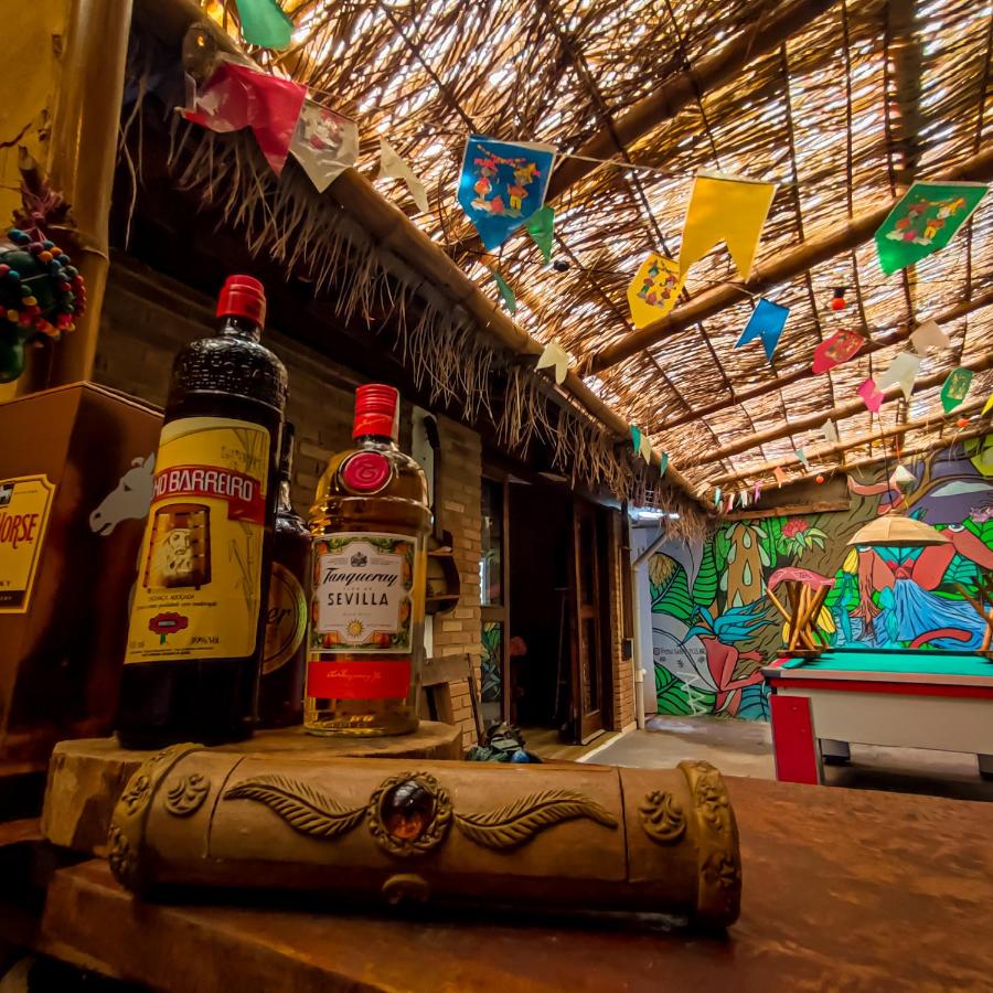 Área compartilhada do Efferus Hostel  com mesa de sinuca, teto rústico de palha e uma parede com desenhos coloridos