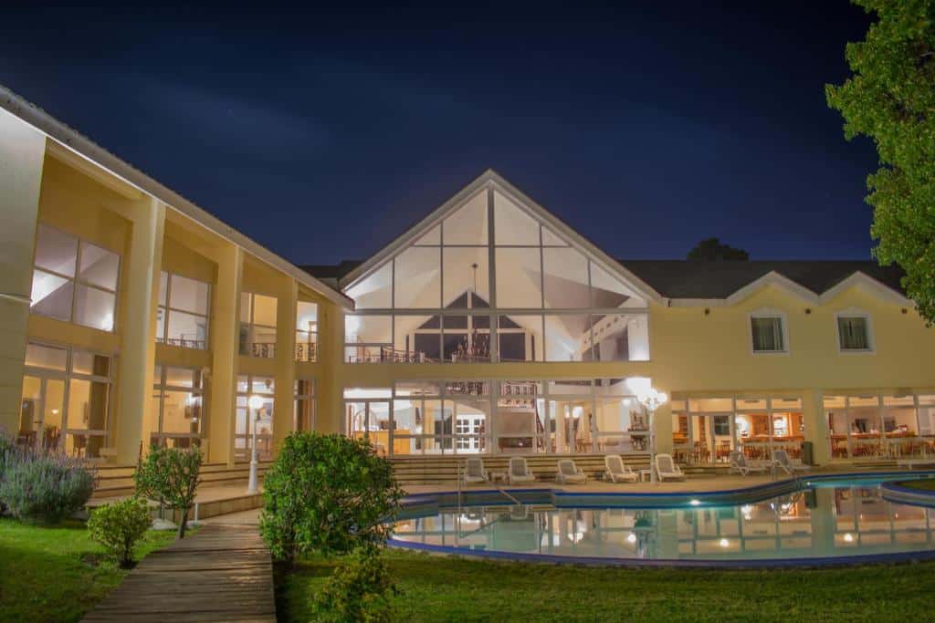 Frente do Parque Hotel Jean Clevers a noite com piscina e cadeiras em volta. Representa hotéis em Punta Del Este.