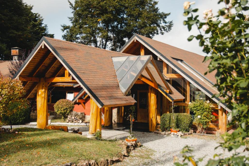 Frente do Peninsula Petit durante o dia com arquitetura feita toda de madeira, gramas na frente e algumas árvores em volta. Representa hotéis em Bariloche.