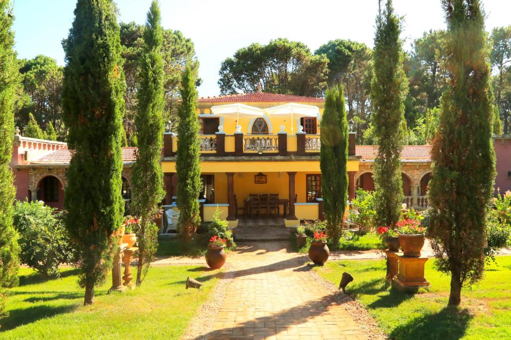Frente do Villa Toscana Boutique Hotel - Adults Only com arquitetura de cor amarela, jardim com árvores na entrada do hotel.