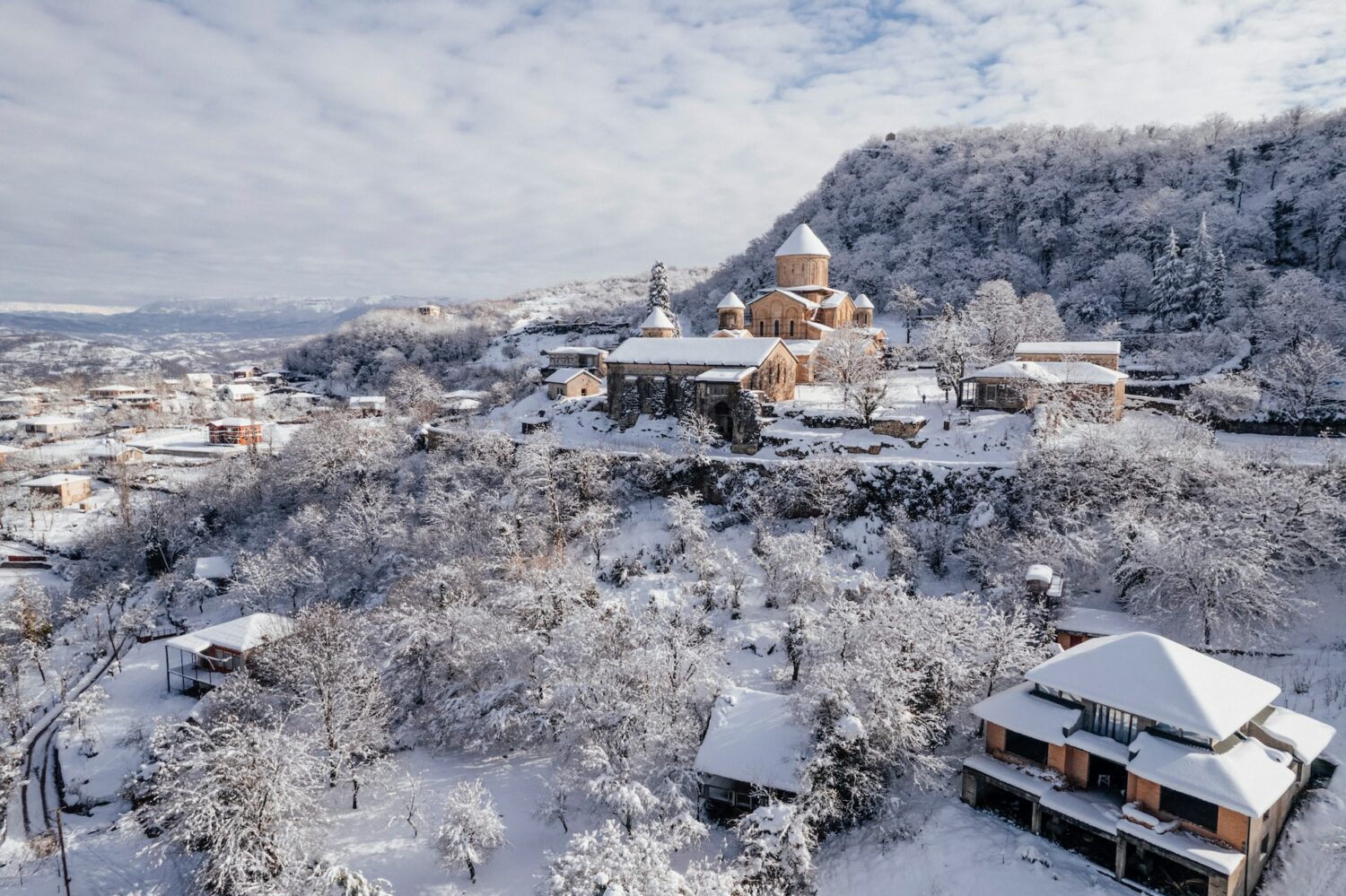 Um mosteiro construído próximo de montanhas totalmente coberto por neve