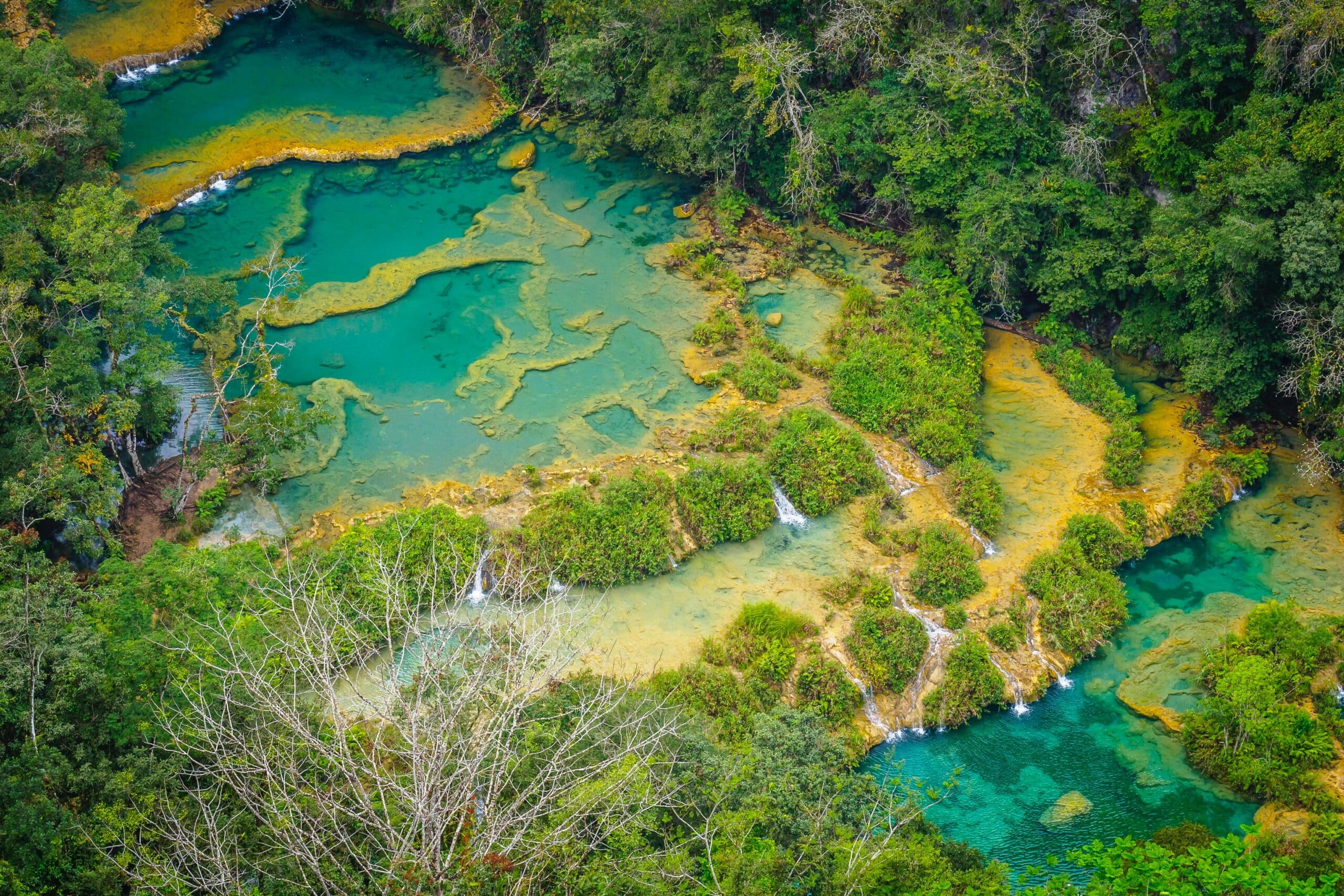 Vista de cima do Lanquen, Guatemala, de aguas azuis em meio a vegetação verde.
