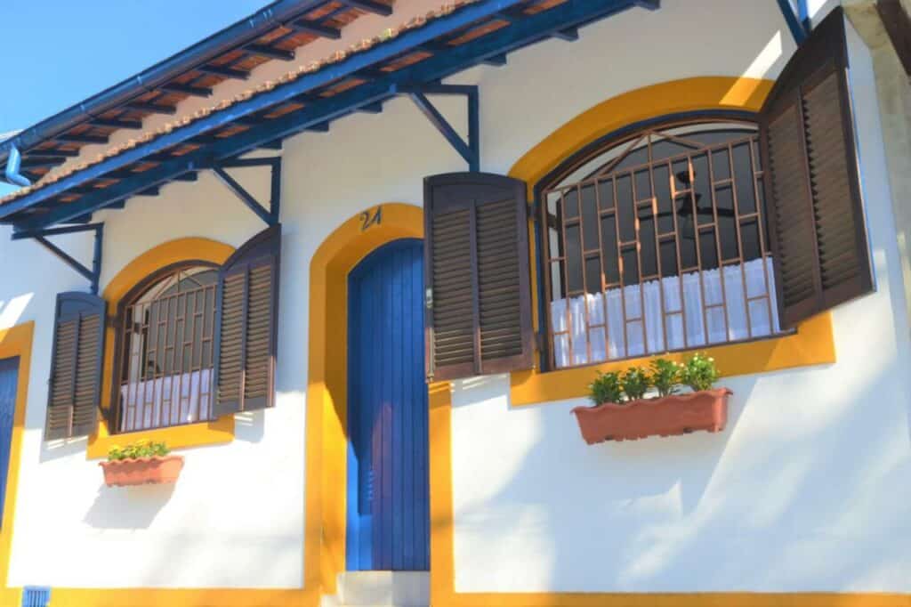 Entrada do Marujo Hostel a casa é toda branca, com as janelas pintadas em amarelo e a porta é azul