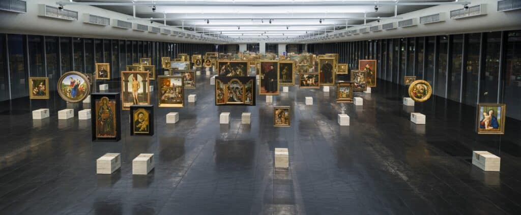 Obras expostas em um amplo espaço dentro do museu com quadros suspensos