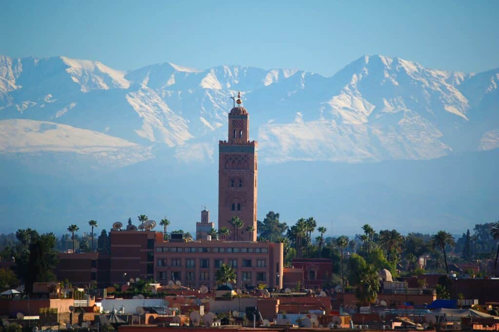 vista da cidade com várias tendas do mercado e montanhas ao fundo com a Mesquita Koutoubia que sobre em um minarete imponente, ilustrando o post de chip celular Marrakesh