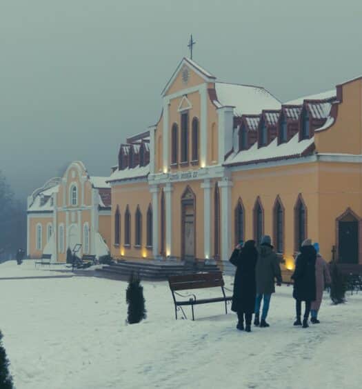 fachada em meio à neve do Museu de História Interativo Sula, em arquitetura clássica soviética em tons de amarelo e com pessoas observando enquanto uma mulher tira foto, ilustrando o post de chi celular Belarus