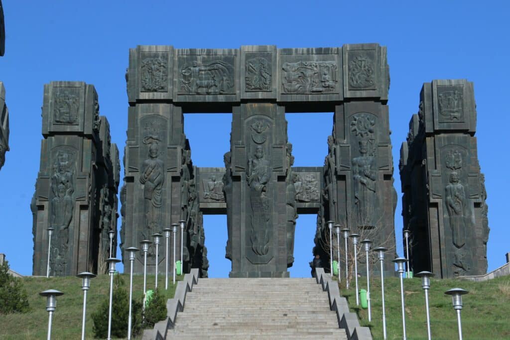 Um monumento de pedra com diversas torres altas e largas com homens esculpidos nelas