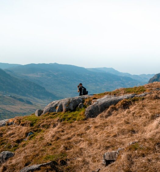 pessoa em meio a montanhas com vegetação bem selvagem no Parque Nacional de Snowdonia, para ilustrar o post de chip celular País de Gales