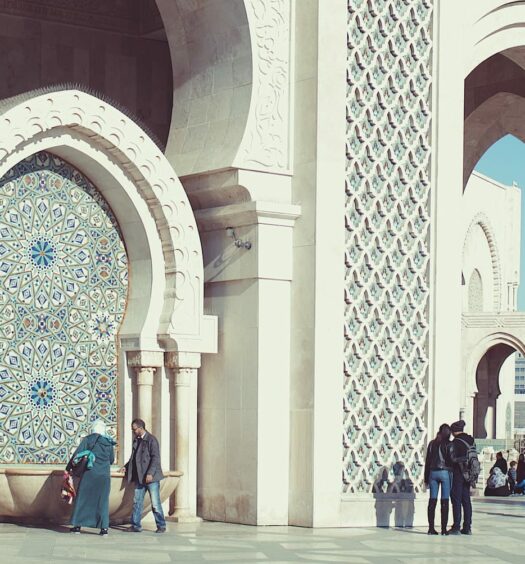 pessoas na Mesquita Hassan II, com arcos ricamente trabalhados ao estilo marroquino em azul e pedras brancas, algumas pessoas estão tirando fotos, para ilustrar o post de chip celular Casablanca