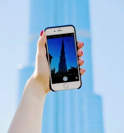 Mão branca de unhas vermelhas tirando foto do Burj Khalifa, edifício em Dubai. - Foto: Tim Gouw via Unsplash