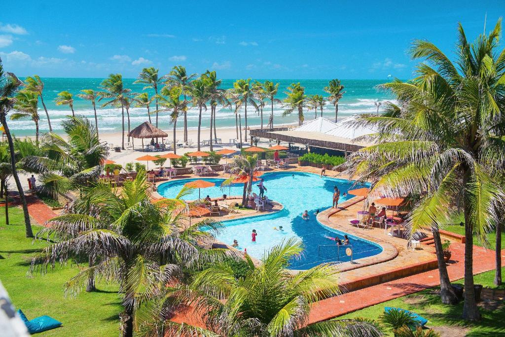 Vista de cima da piscina do Beach Park Hotel – Oceani com palmeiras em volta em frente a praia. Representa hotéis perto do Beach Park