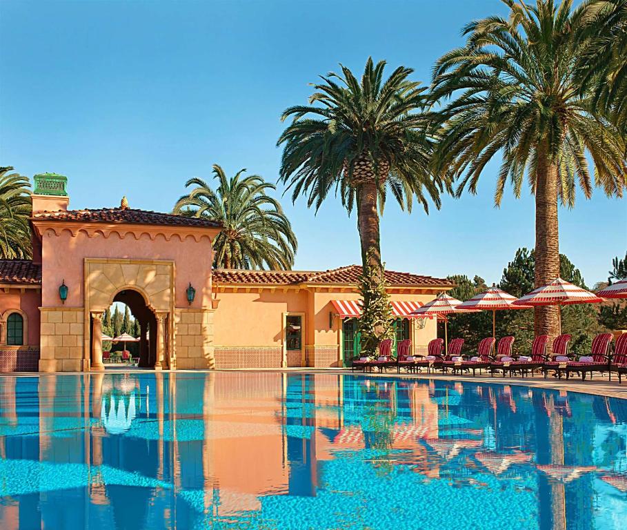 Vista da piscina do Fairmont Grand Del Mar em dia ensolarado com cadeiras em volta da piscina. Representa hotéis em San Diego