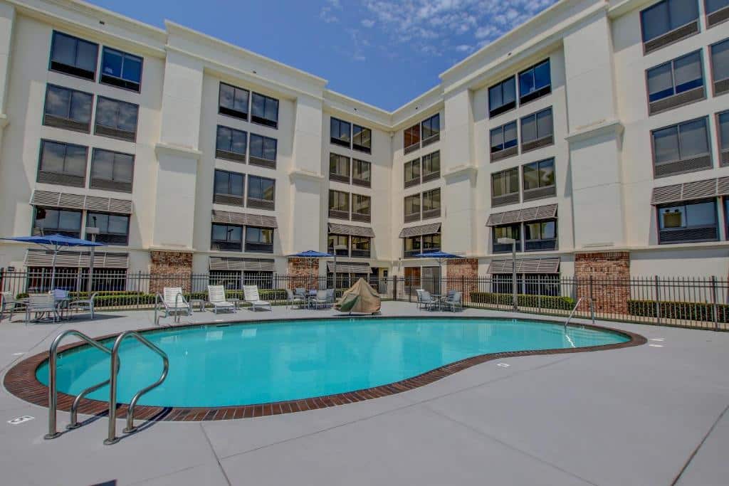 Vista da piscina do Hampton Inn by Hilton San Diego – Kearny Mesa com cadeiras perto da piscina e ao fundo a hospedagem. Representa hotéis em San Diego.