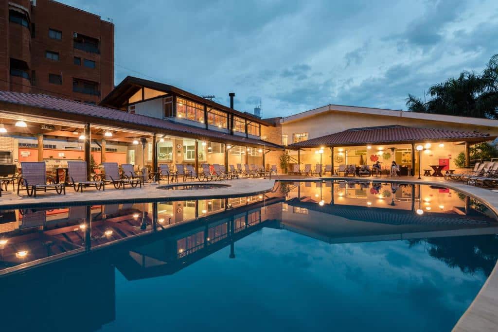 Vista da piscina do LS Villas Hotel & Spa com cadeiras em volta dela. Representa pousadas na Águas de São Pedro