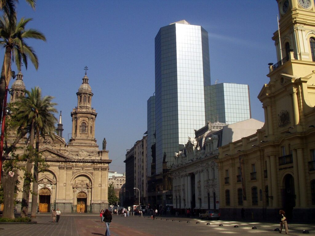 Catedral bege ao lado de construções históricas e um prédio moderno para ilustrar o post sobre chip de celular para Santiago. - Foto: Simon via Pixabay