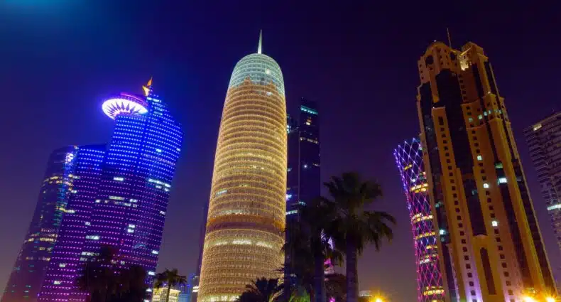 Arranha-céus iluminados à noite para ilustrar o post sobre chip de celular para o Qatar. - Foto: Mike Swigunski via Unsplash