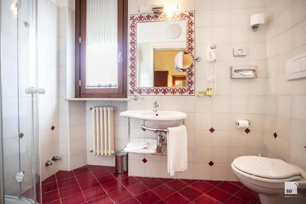 banheiro amplo do Hotel Alessandro Della Spina, com ambiente adaptado para PCDs, pia e banheiro mais baixos