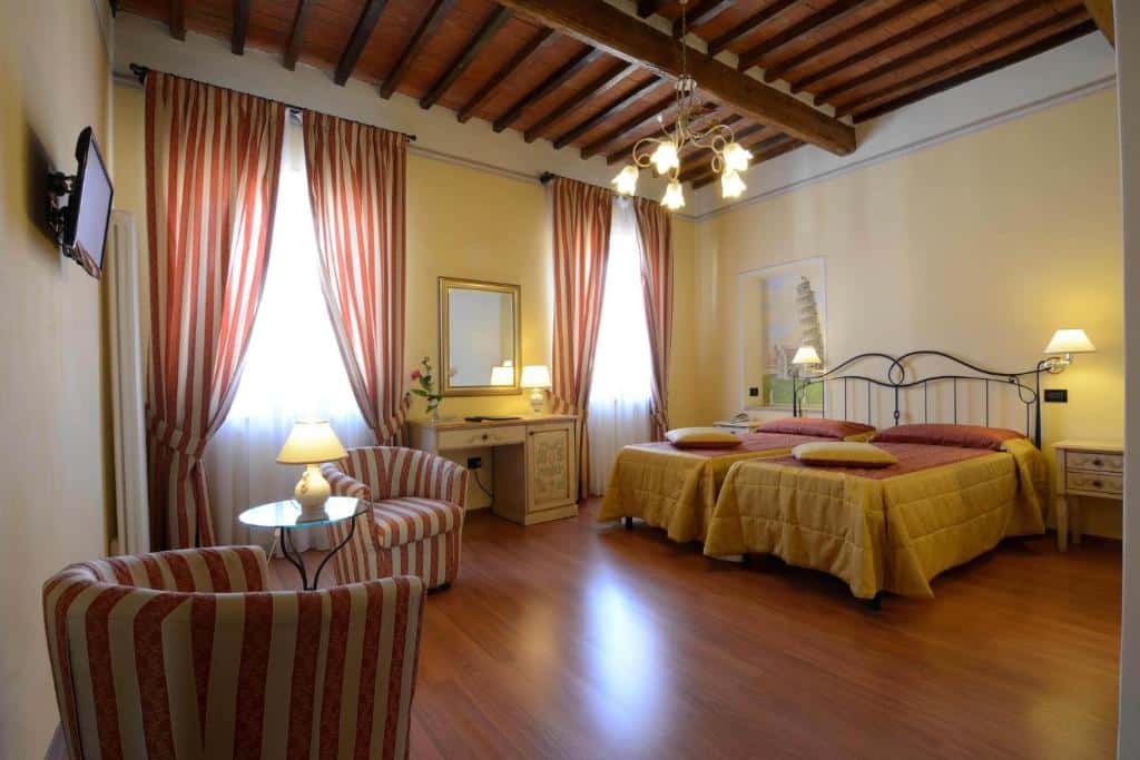 quarto amplo do Hotel Di Stefano com duas camas grandes, duas janelas também bem grandes com cortina, duas poltronas e luminária de teto