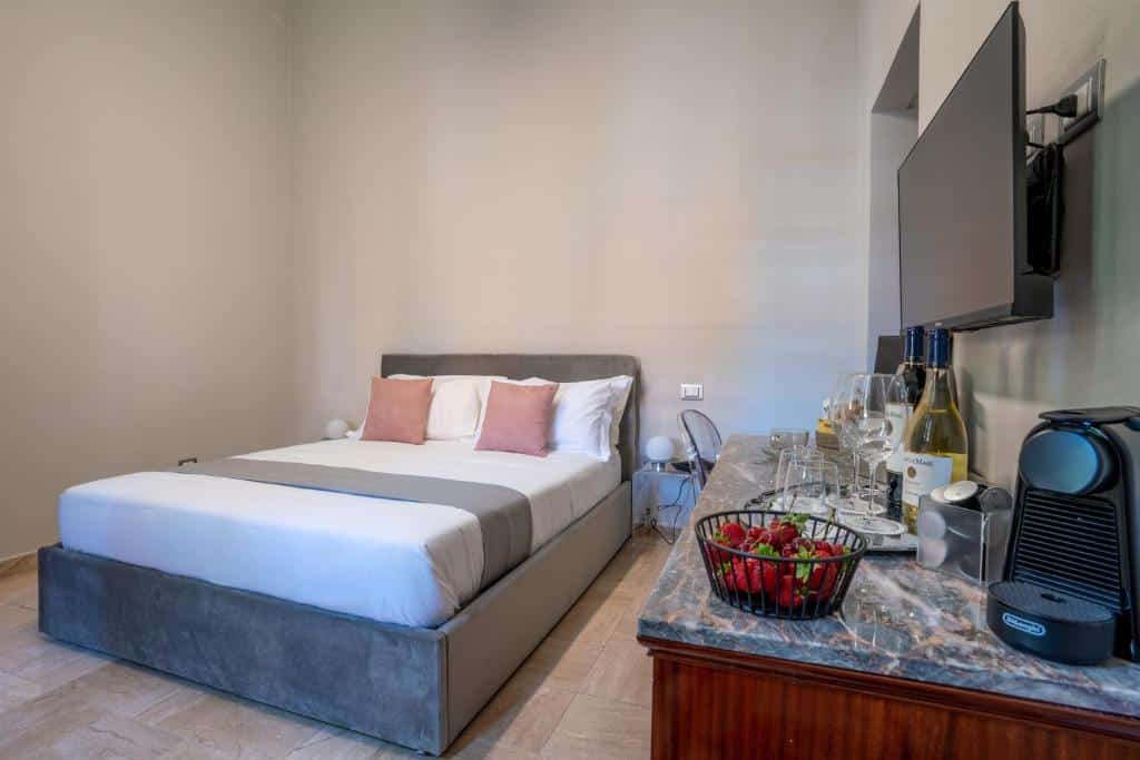 quarto do The Rif - Boutique Hotel, um dos hotéis em Pisa, com cama de casal, bancada com frutas e tv em detalhes laranja e cinza claro