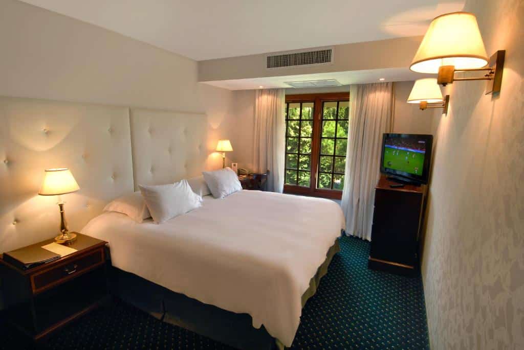 Quarto do Barradas Parque Hotel & Spa com cama de casal ampla, com duas cômodas ao lado da cama, TV no lado esquerdo em cima de uma cômoda de madeira.