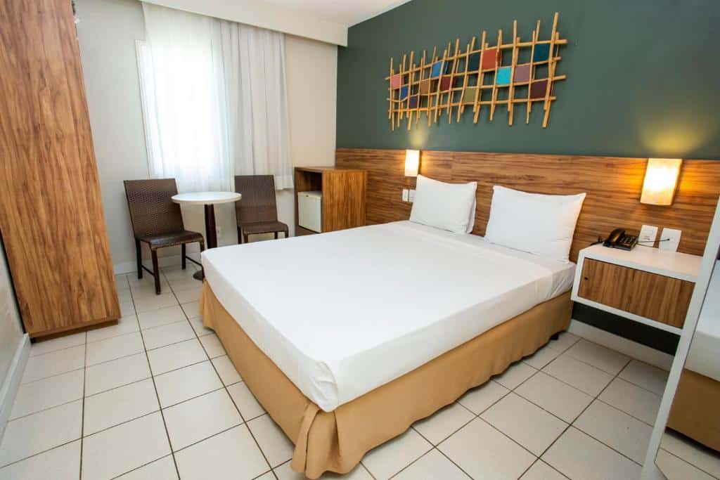 Quarto do Beach Park Hotel – Oceani  com cama de casal, frigobar do lado esquerdo e duas cadeiras e uma mesa.