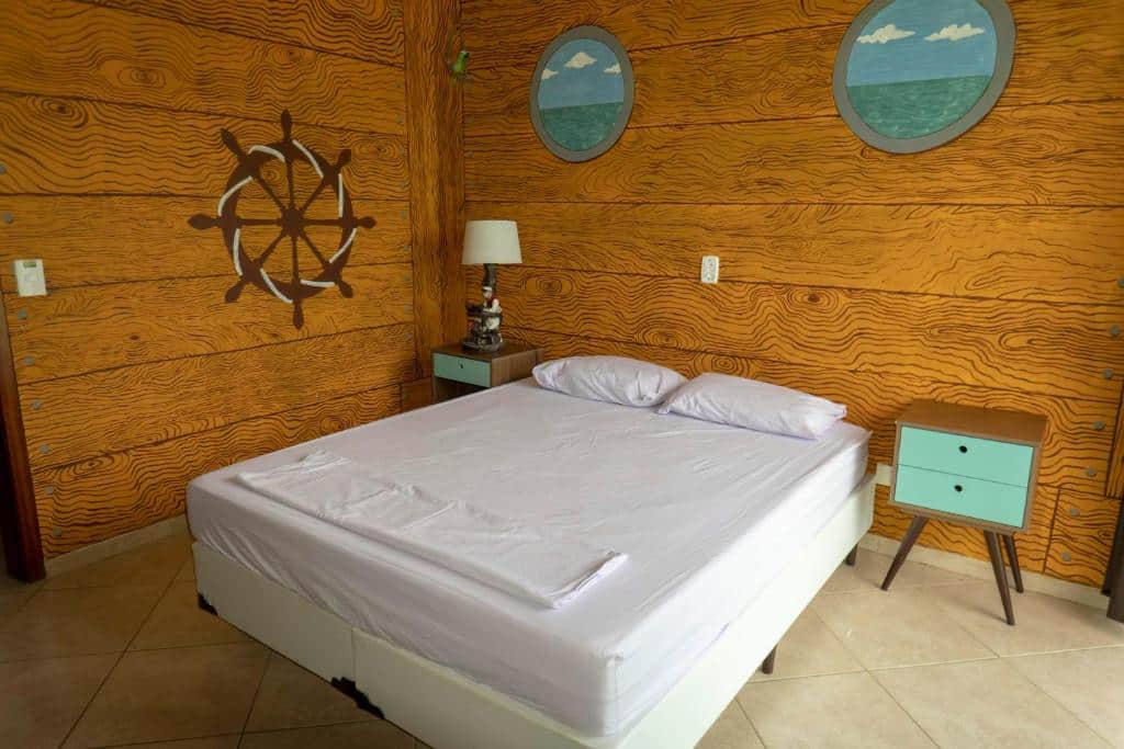 Quarto com uma cama de casal, duas mesinhas de cabeceira e uma decoração marítima no Green Haven Hostel