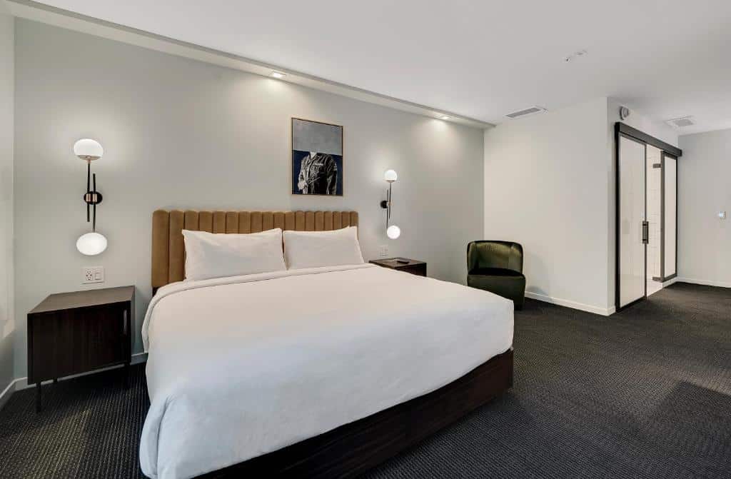 Quarto do The Guild Hotel, San Diego, a Tribute Portfo com cama de casal, duas cômodas com luminária pendurada na parede ao lado.