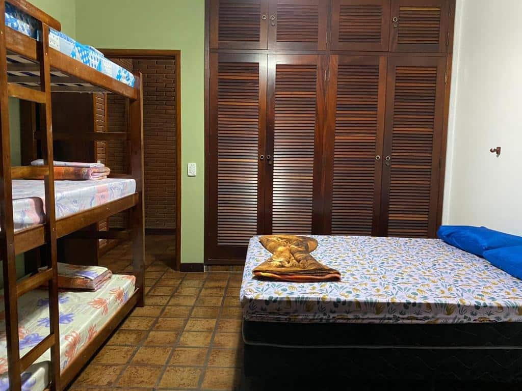Quarto no Hostel Trópico de Capricórnio - Vermelha do Centro com um armário de madeira embutido, uma cama de casal e uma beliche com três lugares