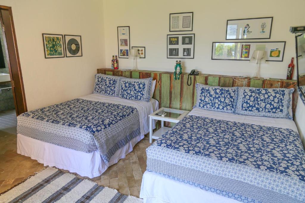 Quarto no Hotel Boutique Ananas com duas camas de casal, uma cabeceira rústica com abajures e enfeites rústicos, para representar resorts em Ilhabela