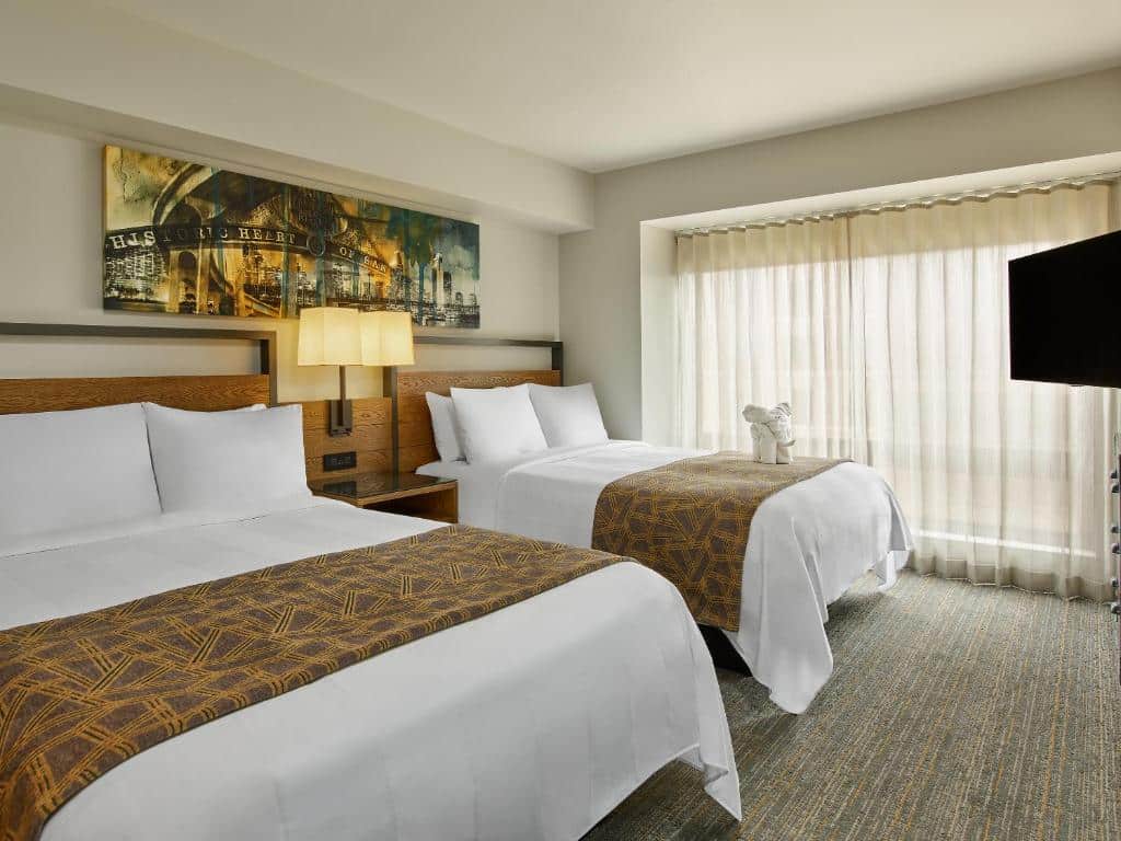 Quarto do Marriott Vacation Club Pulse, San Diego com duas camas de casal, uma cômoda que separa as duas camas ao meio e TV do lado esquerdo.