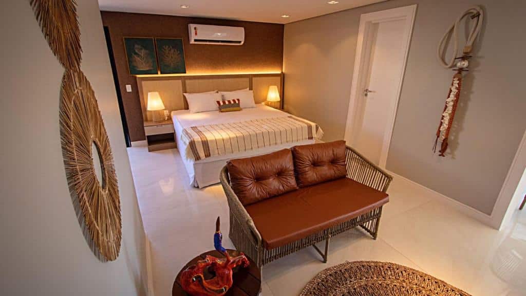 Quarto do Paraiso Beach Hotel com cama de casal, duas luminárias ao lado da cama e sofá em frente a cama.