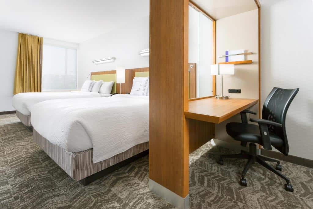 Quarto do SpringHill Suites by Marriott San Diego Mission Valley com duas cama de solteiro com cômoda com luminária no meio. Mesa de trabalho com cadeira do lado direito.