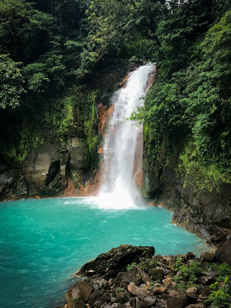 Cachoeira no meio de vegetação para ilustrar o post sobre chip de celular para Costa Rica. A água cai em um rio azul celeste. - Foto: Marcelo Villalobos via Unsplash