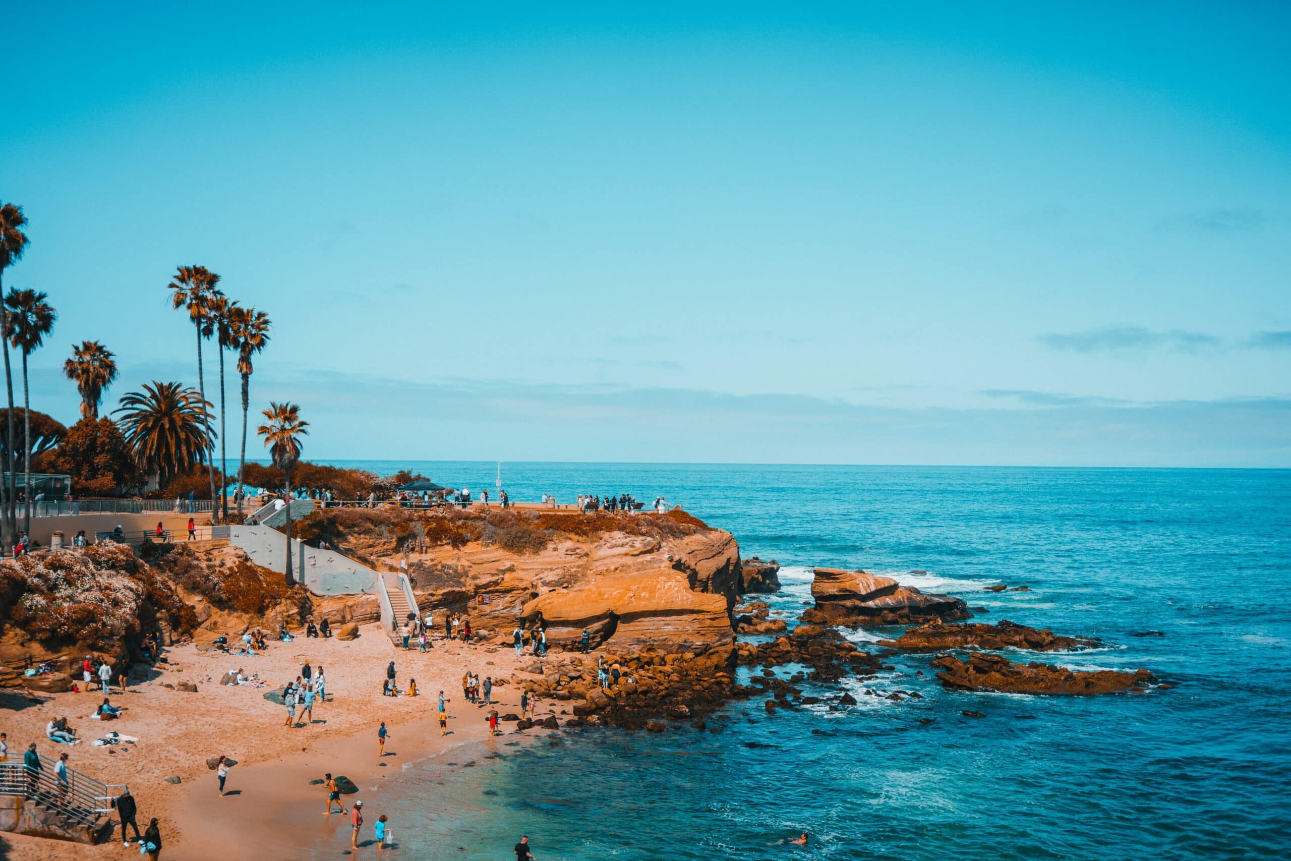 Vista de pessoas na areia da praia em San Diego, Califórnia, Estados Unidos com mar azul e céu limpo e ensolarado.